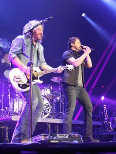 Members of the Eli Young Band perform on stage bathed in purple light