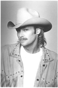 a publicity photo of Alan Jackson from 1993. He is wearing a fringed jacket and his signature cowboy hat.