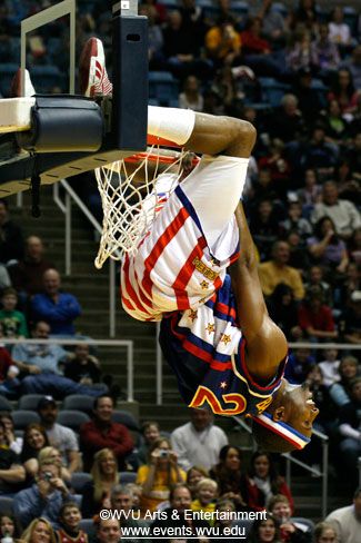 A Globetrotter hangs upside down from one of the basketball hoops at the Coliseum.