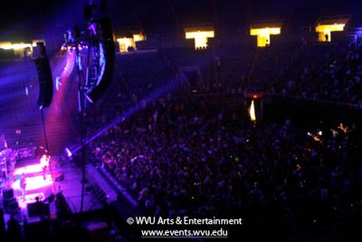 Photo: wide shot of Widespread Panic on stage at the WVU Coliseum with a full crowd watching the show.