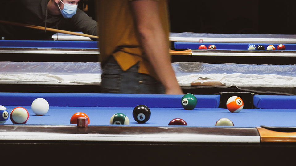 Pool table with various pool balls spread out in the middle of a game