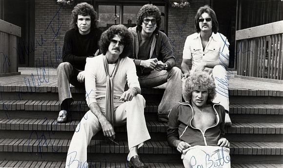Black and white publicity photo of Wild Cherry from 1977 with band members setting on steps