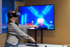 a female student wearing a virtual reality headset gesturing to play the game