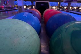 Bowling balls glowing neon under blacklight wait in the ball return