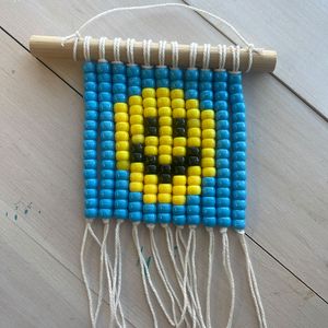 wall hanging made with beads to form a smiley face