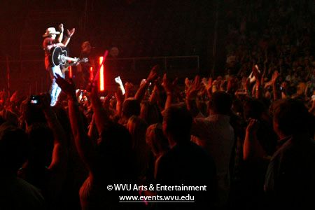 Photo of Jason Aldean on stage and clapping in unison with the crowd at the WVU Coliseum