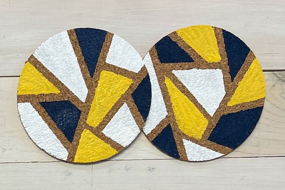 Cork coasters painted in blue, gold and white geometric shapes