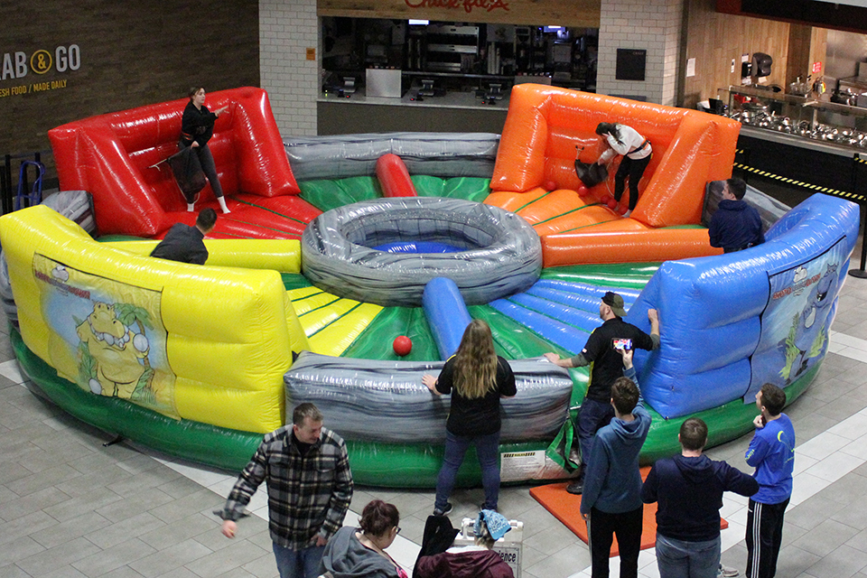 Students attached to bungee cords work to get the most balls out of the center of an inflatable arena.