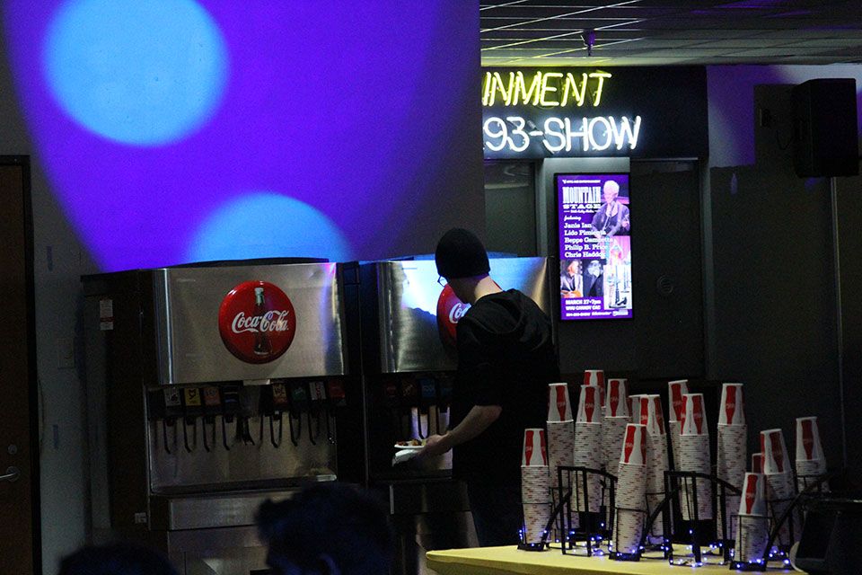 A student serves themselves soda while the blue strobe lights play in the background