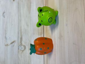 ceramic banks. one shaped like a pig and painted green. the second is shaped like a pumpkin and painted orange and green.