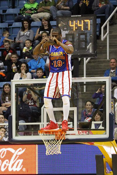  a member of the Globetrotters stands atop the hoop inside the Coliseum