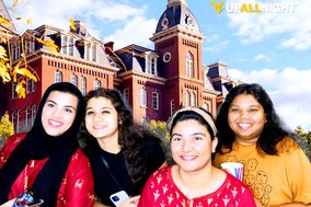Four students pose for a photo booth photo with Woodburn Hall in the background.
