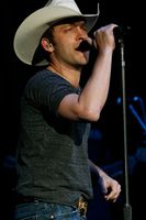 Justin Moore wearing a white cowboy hat and singing at the Coliseum in 2011