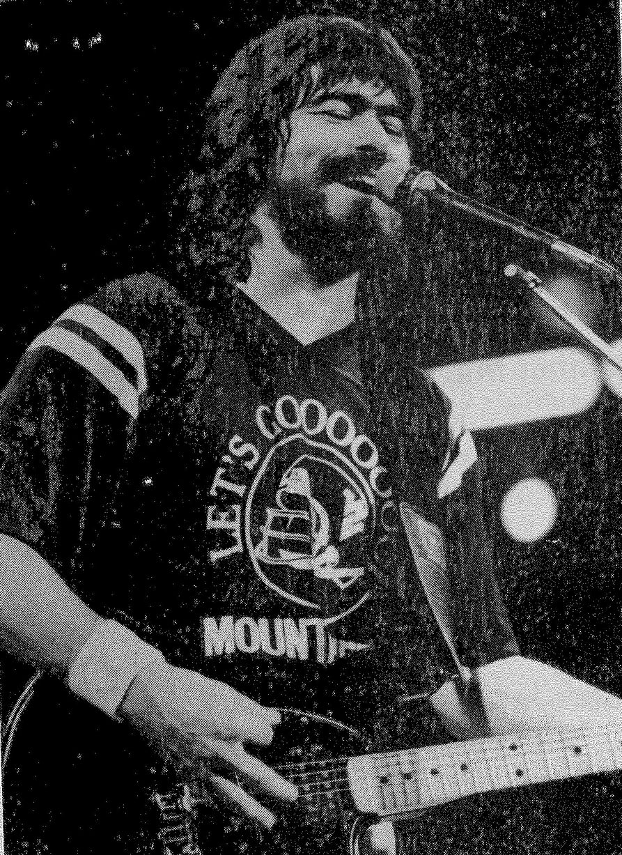 Black and white photo of Randy Owen performing on stage at the Coliseum while wearing a WVU t-shirt.