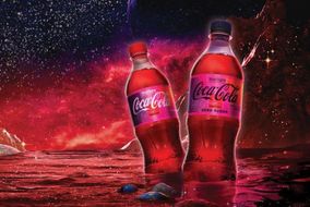 two plastic bottle of Coca-Cola Starlight with a background drawn to simulate the galaxy. Color scheme includes reds and blacks.