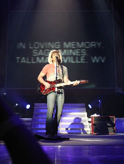 Brad Paisley sings on the Coliseum stage in front of the video screens that reads "In loving memory. Sago Mines. Tallmansville, WV."