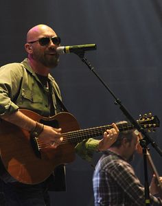 Corey Smith wearing dark glass sings and play guitar on stage in 2014