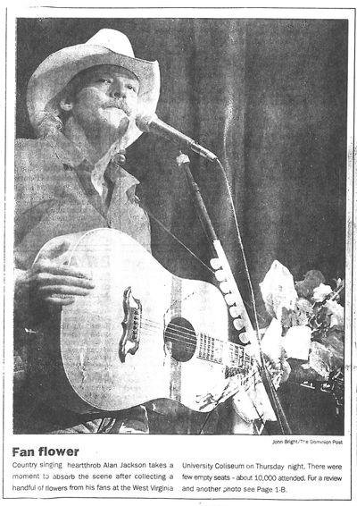 Country singing heartthrob Alan Jackson takes a moment to absorb the scene after collecting a handful of flowers from his fans at the West Virginia University Coliseum on Thursday night. Photo from The Dominion Post Sept. 17, 1993