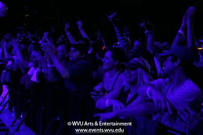 A crowd of fans on the floor watch the concert.