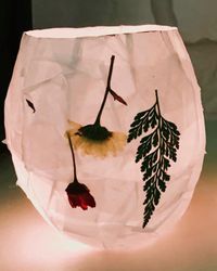 Photo of a lit botanical luminary with flowers and leaves decorating it