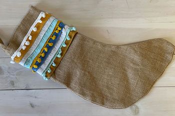 burlap holiday stocking decorated with pom poms