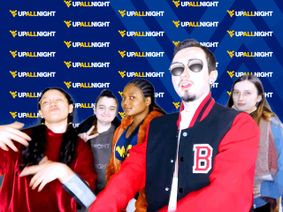 Group of students wearing hoodies and jackets pose for a photo at the photo booth.