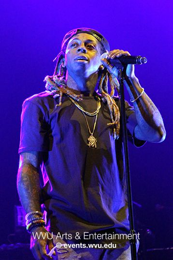 Lil Wayne sings on stage bathed in purple lights